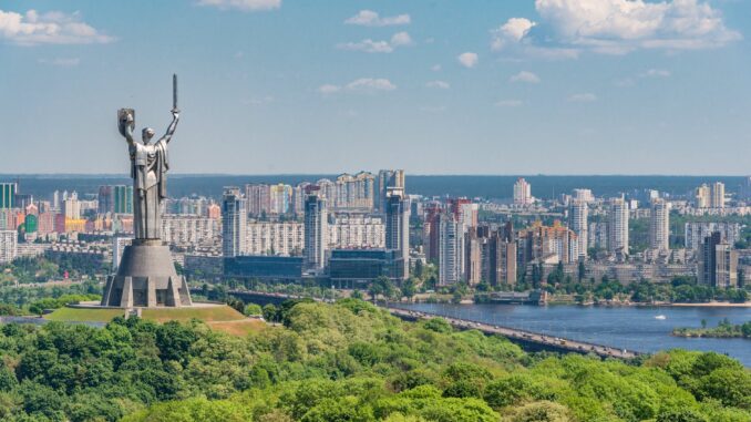 motherland monument among green trees on embankment in kiev