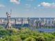 motherland monument among green trees on embankment in kiev