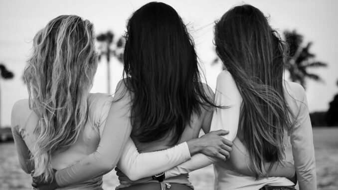 grayscale and selective focus photography of three women