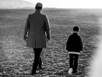 black and white photo of a person walking with a child