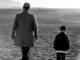 black and white photo of a person walking with a child